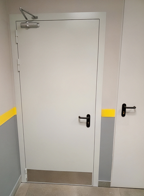 Белая противопожарная дверь с доводчиком и отбойной пластиной Белая противопожарная дверь с доводчиком и отбойной пластиной